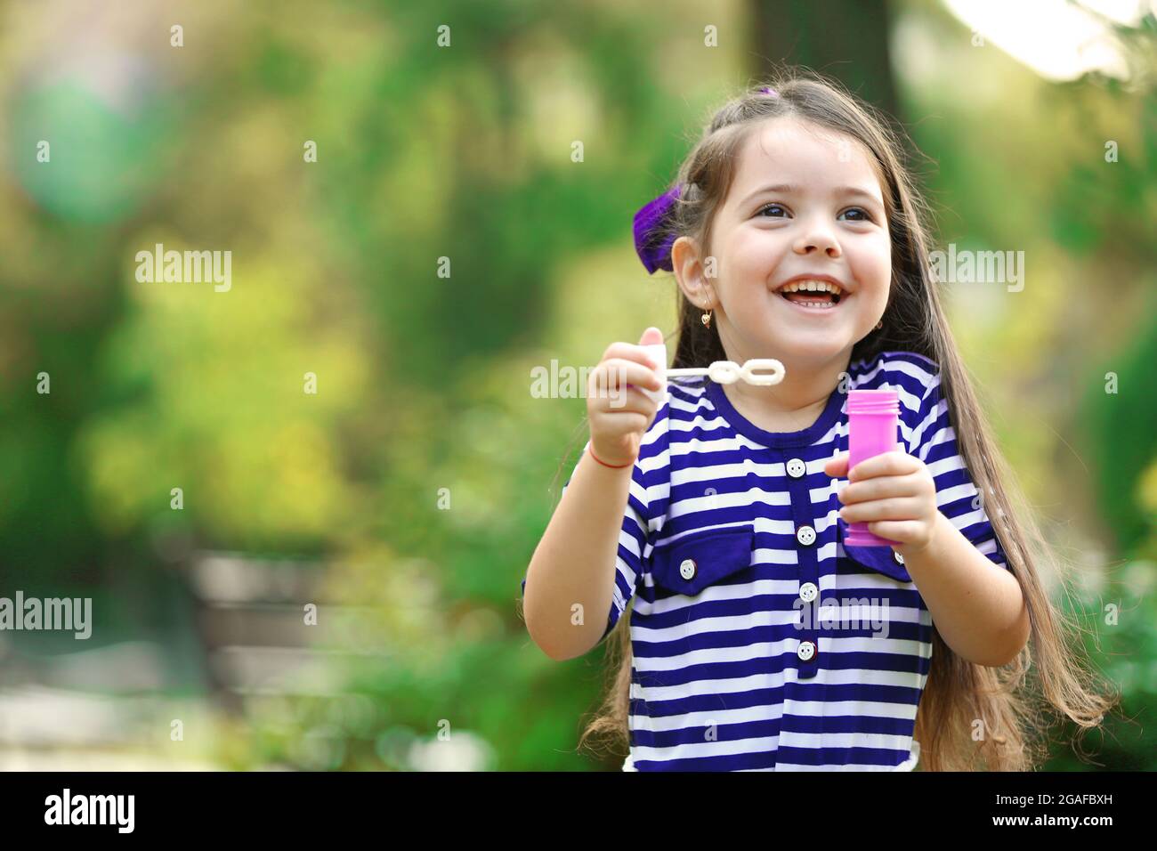 Happy little girl with bubbles in the park Stock Photo - Alamy