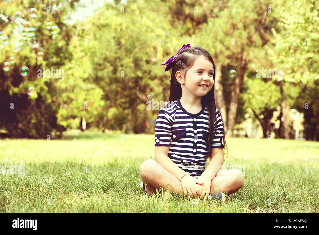 Happy little girl with bubbles on the green grass in the park Stock ...