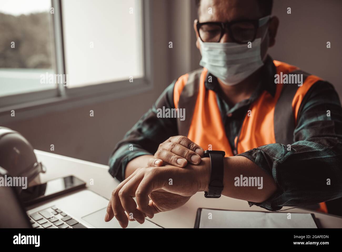 An engineer checks the time by looking at a smartwatch. Stock Photo