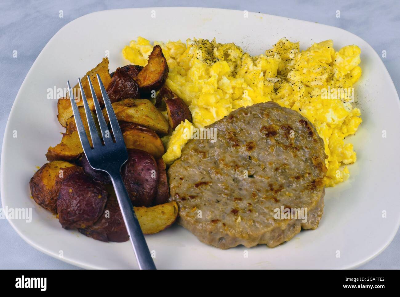 scrambled eggs top with black pepperand sausage patty served with home