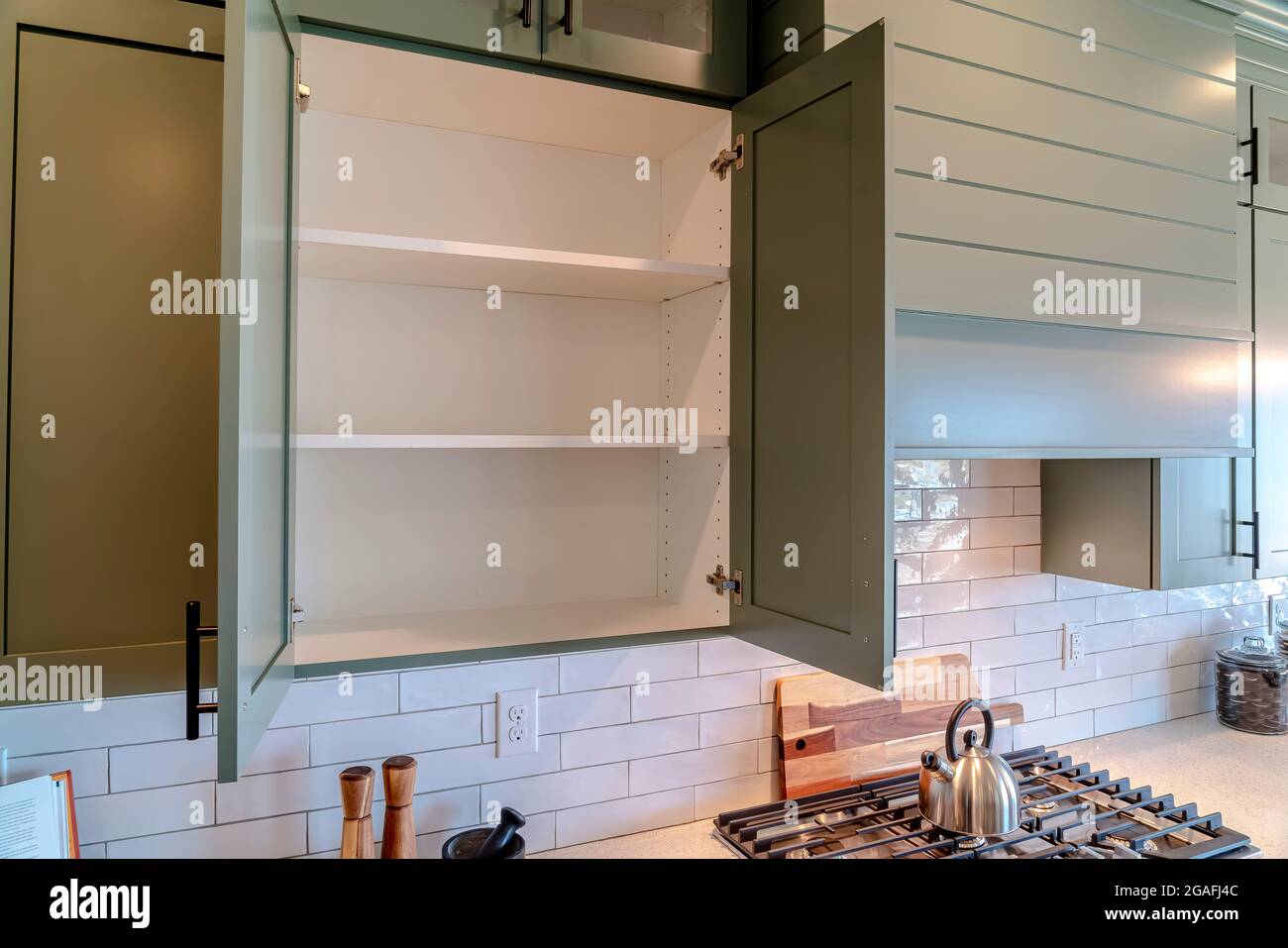 Wall cabinet and exhaust hood over cooktop and countertop inside a home kitchen Stock Photo