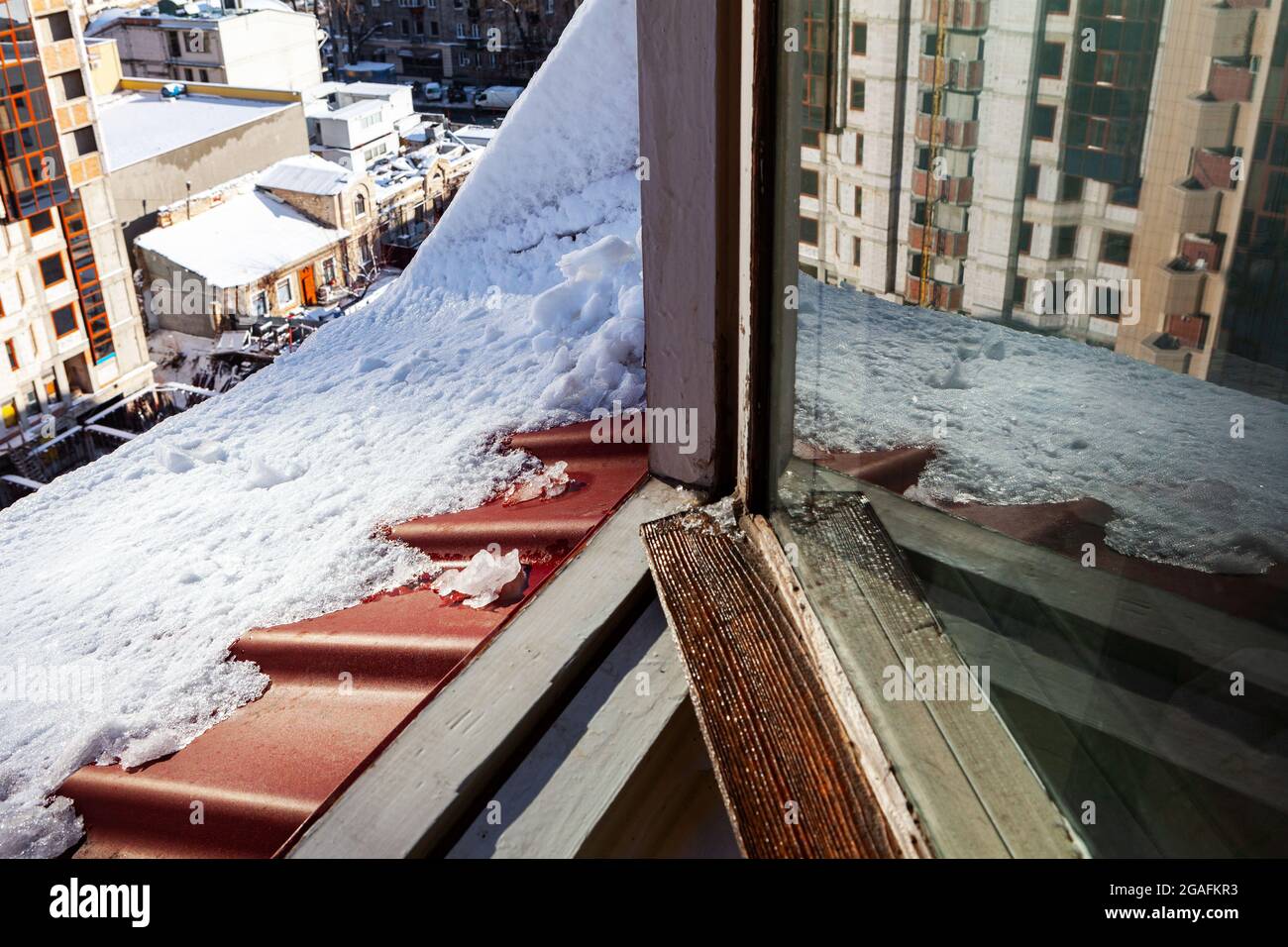 Melting snow on the attic window . Winter city view from the loft Stock