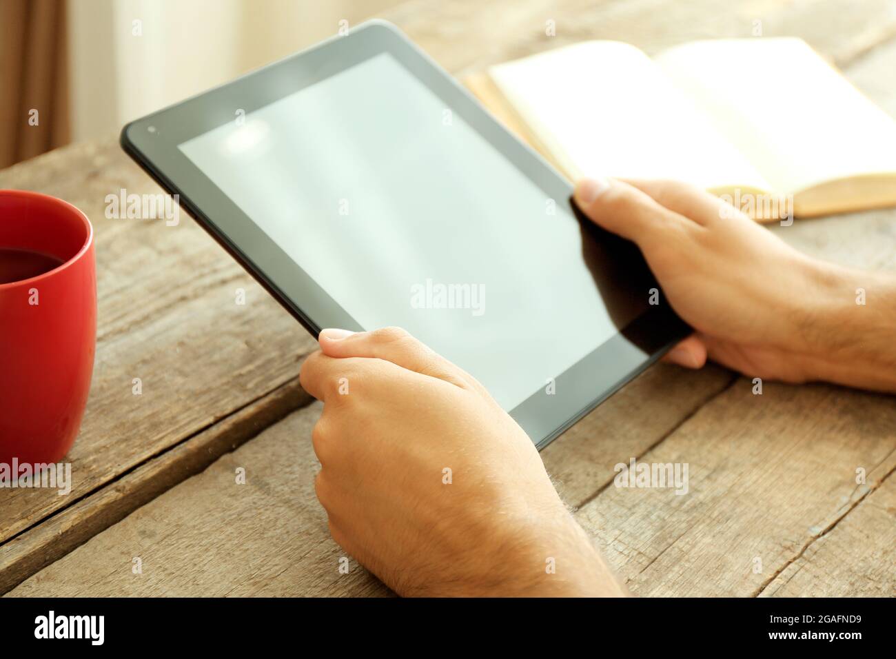 Tablet In Man S Hands Book And Cup Of Tea On Wooden Table Stock Photo Alamy