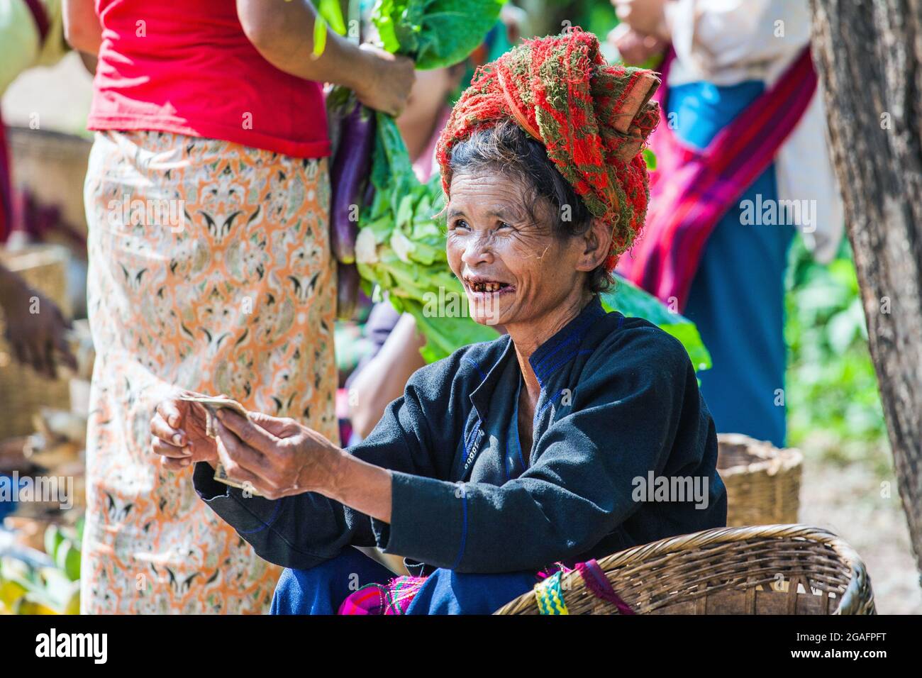 Burmese female from Pao/Pa-o ethnic hill tribe with betel nut stained teeth selling vegetables at Mine Thauk Market, Nyaungshwe, Myanmar Stock Photo
