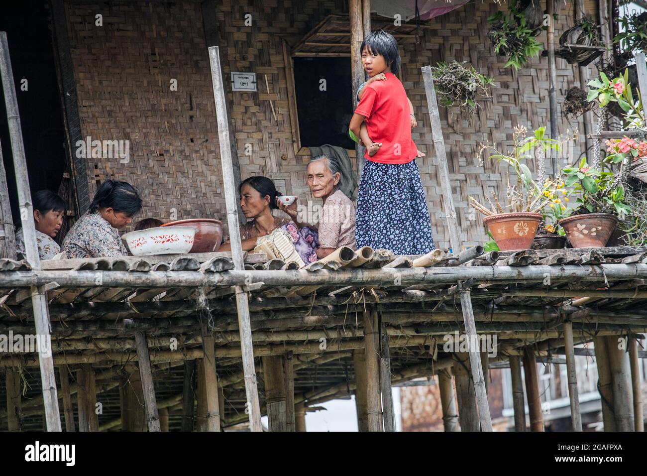 Family seated on deck outside wooden stilt house, Inle Lake, Myanmar Stock Photo