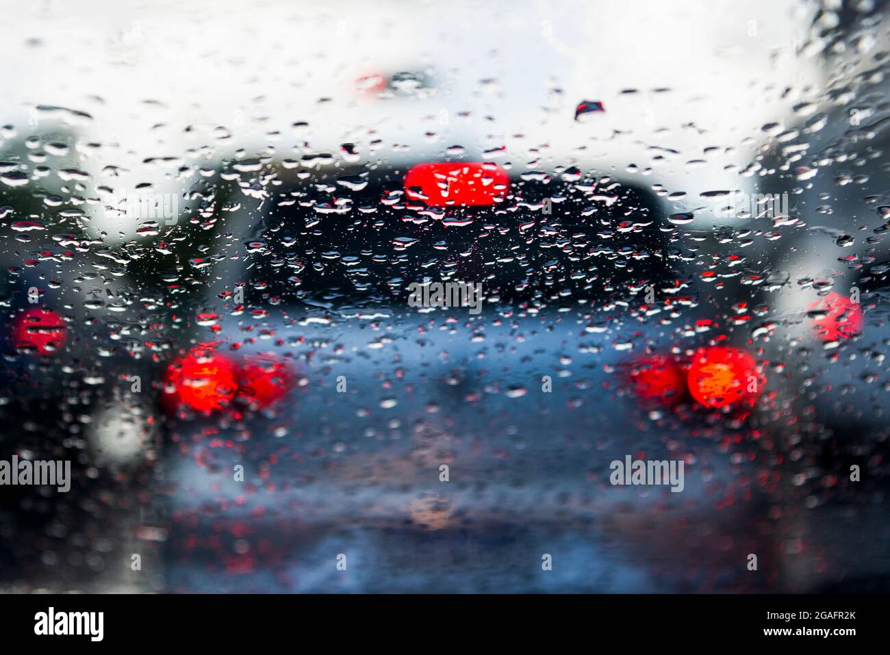 Bokeh, chuva, gotas de água pelo vidro do carro. Dia chuvoso. Lanternas de carros desfocadas. Colorido. Stock Photo