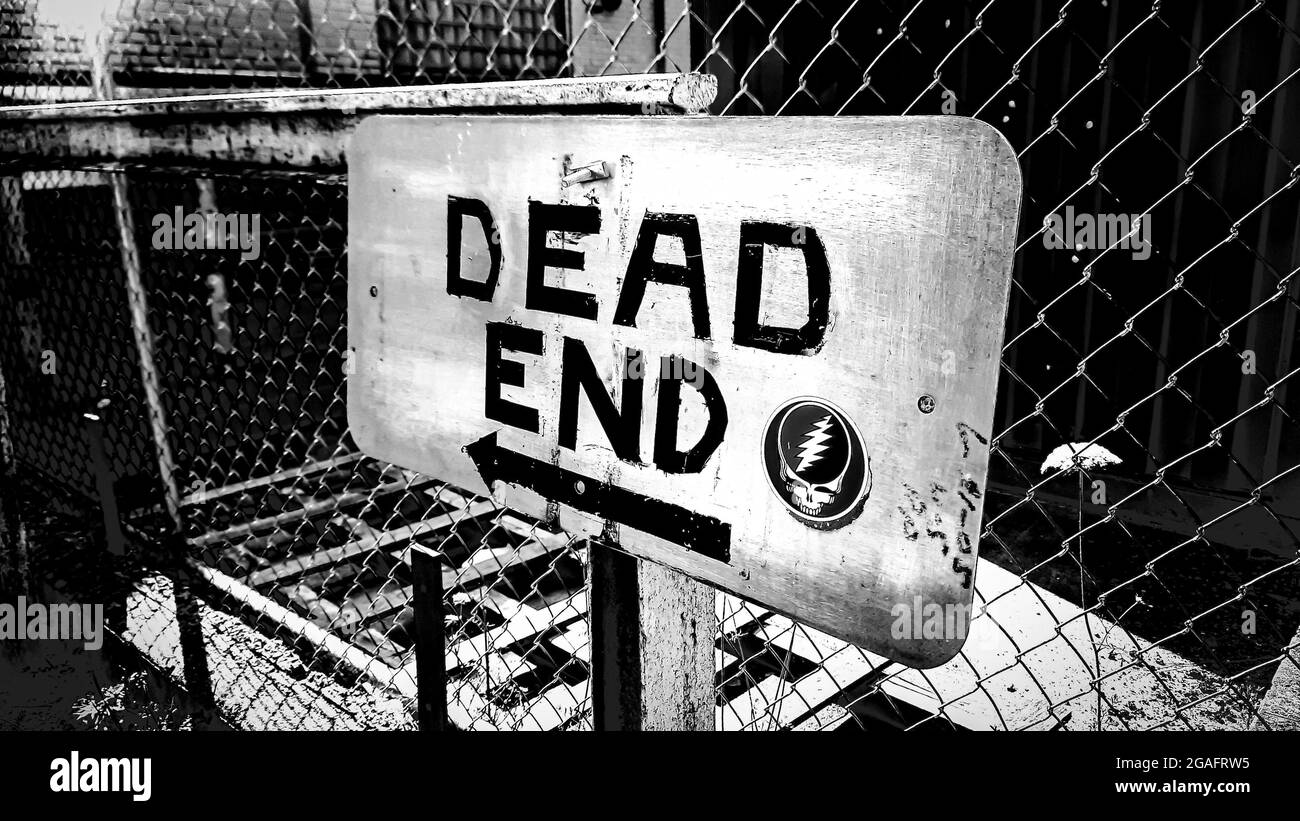 Grayscale shot of a DEAD END sign attached to a cyclone wire fence