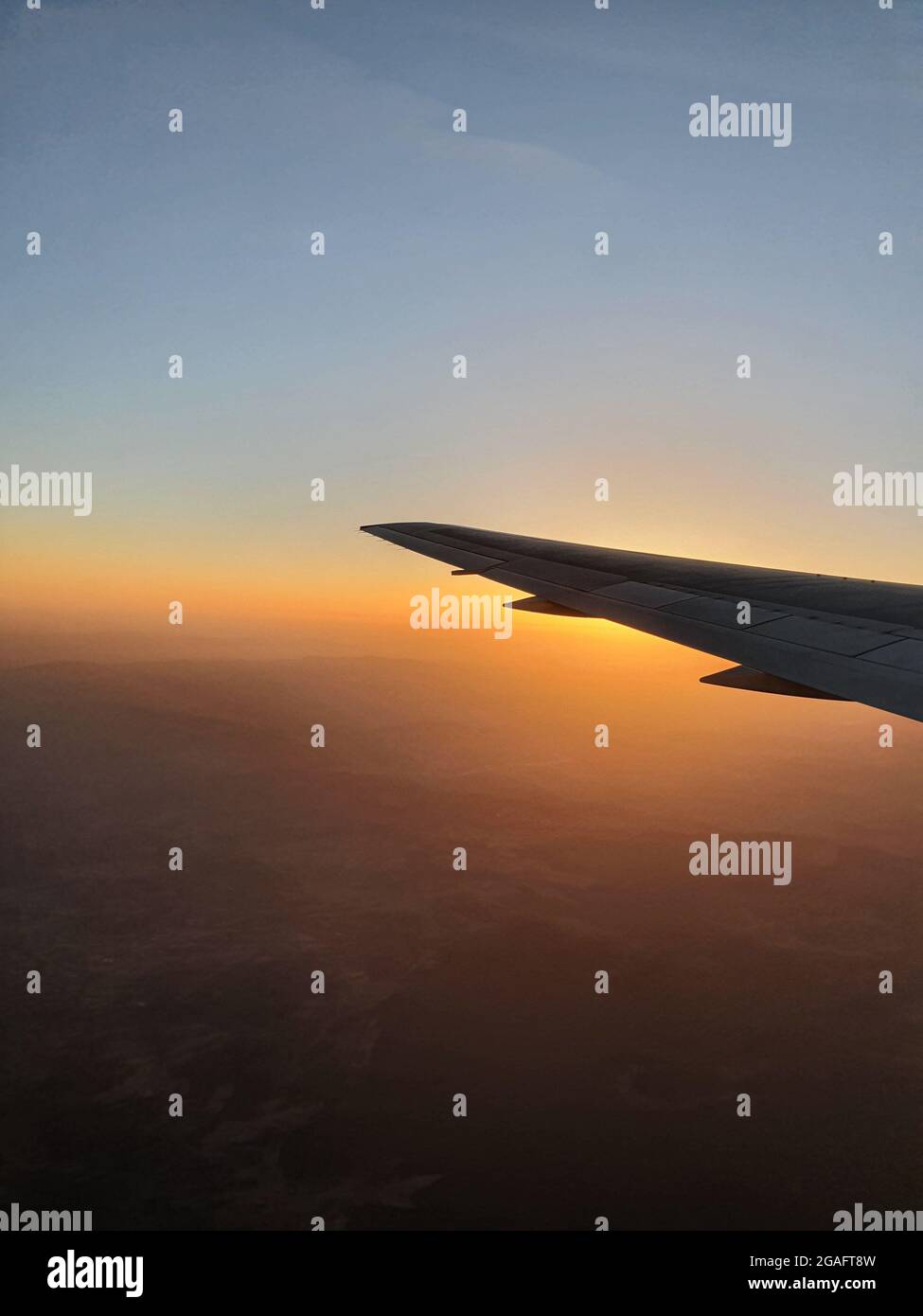 View of the sky and the wing with the iluminator of the aircraft. Lovely sunset, mountains and atmosphere of travel. Stock Photo