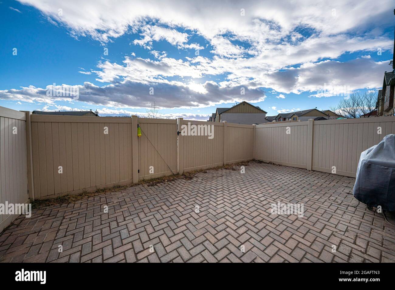 Backyard of a house with fence and bricks and a view of vibrant sky Stock Photo