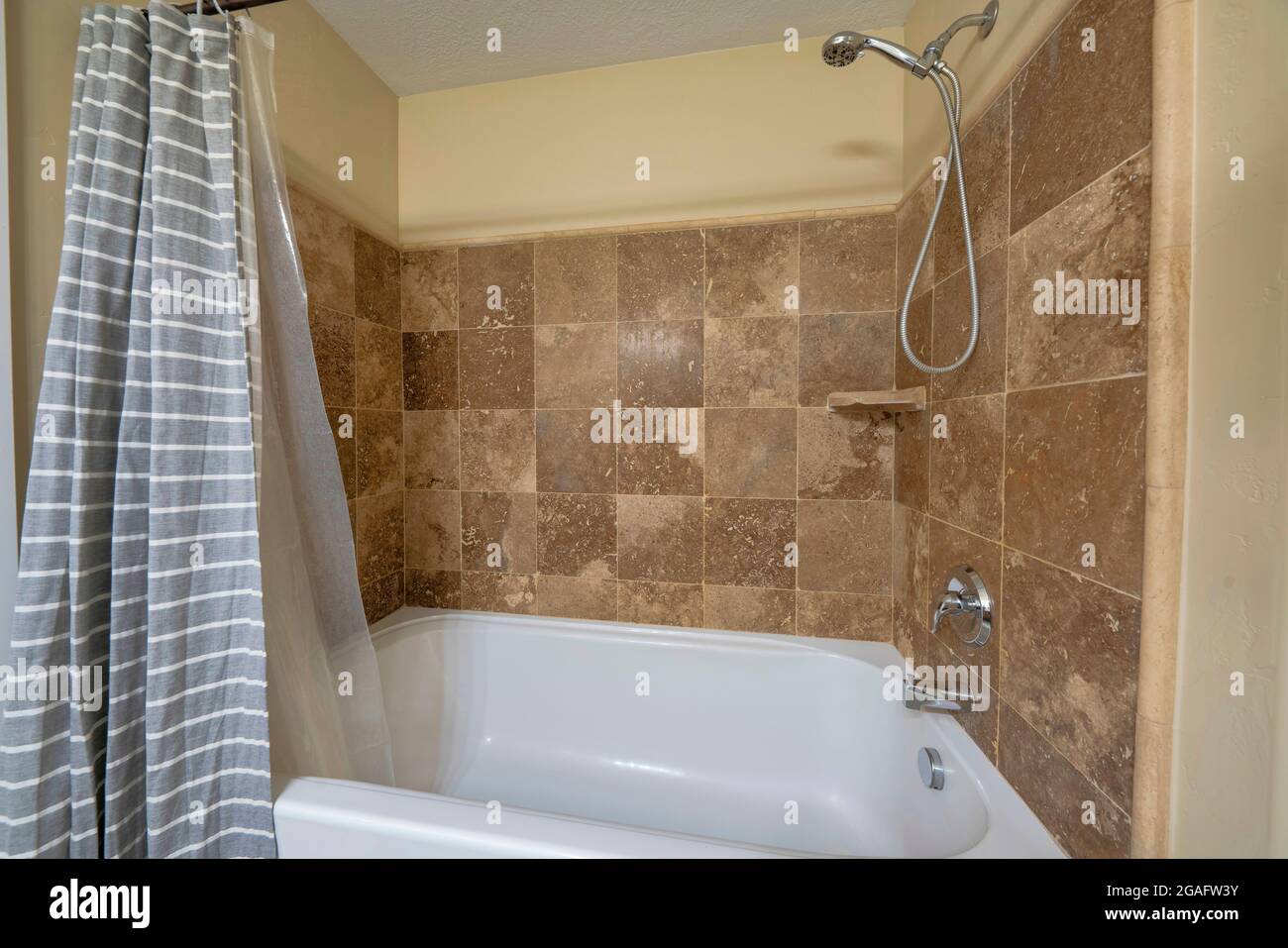 Bathtub inside a bathroom with brown tiles wall surround Stock Photo