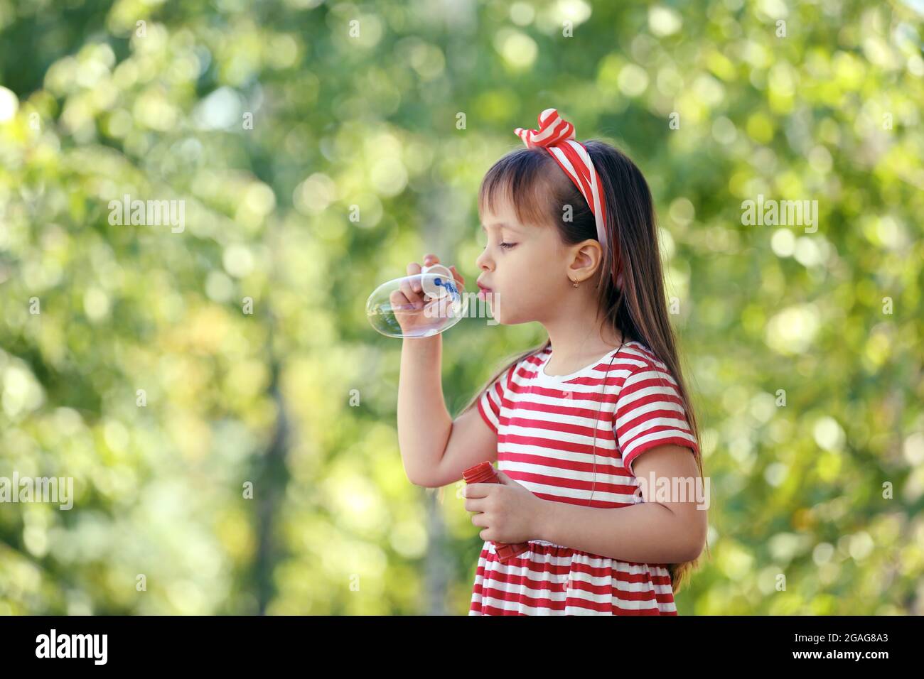 Little girl playing with bubbles in the park Stock Photo - Alamy