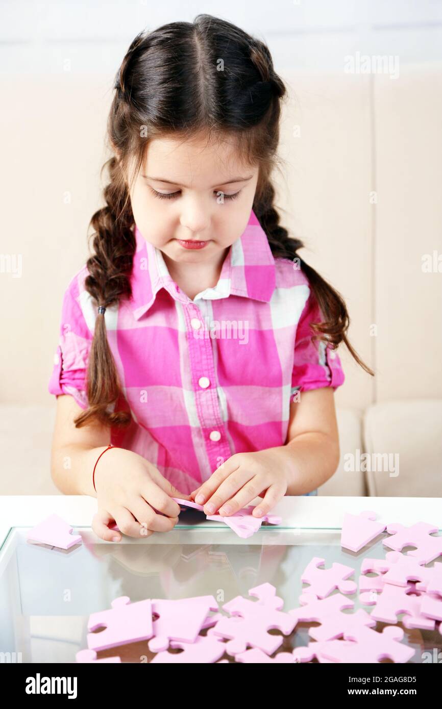 Cute little girl playing with puzzles on home interior background Stock ...