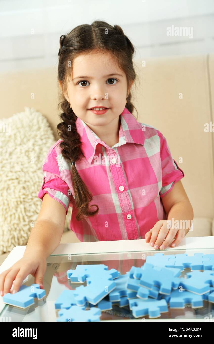 Cute little girl playing with puzzles on home interior background Stock ...