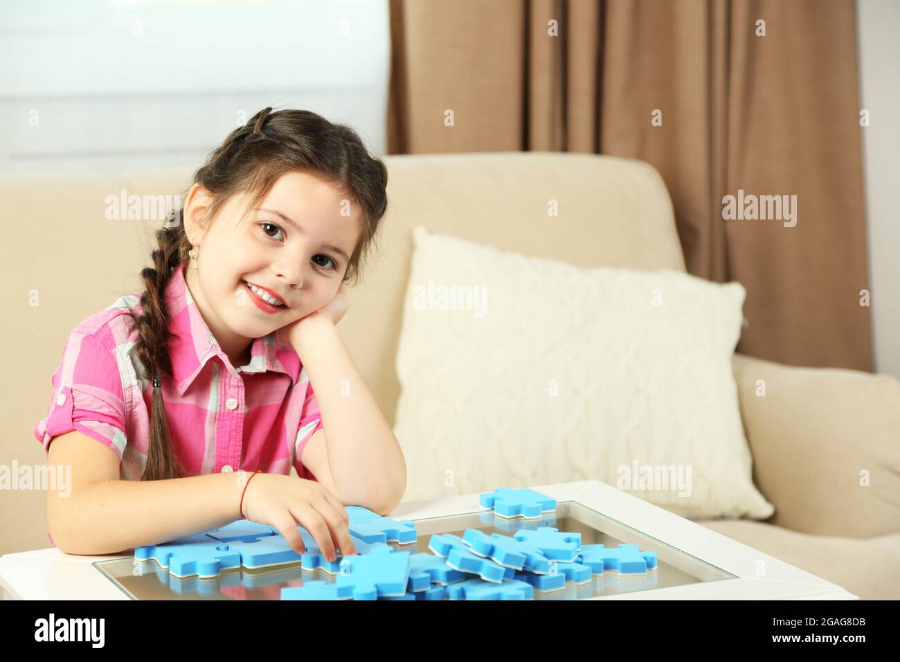 Cute little girl playing with puzzles on home interior background Stock ...