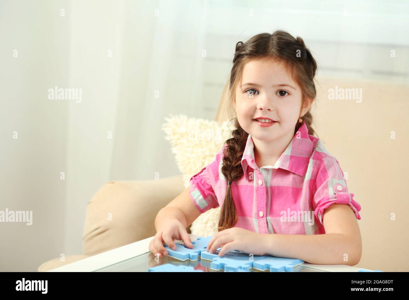 Cute little girl playing with puzzles on home interior background Stock ...