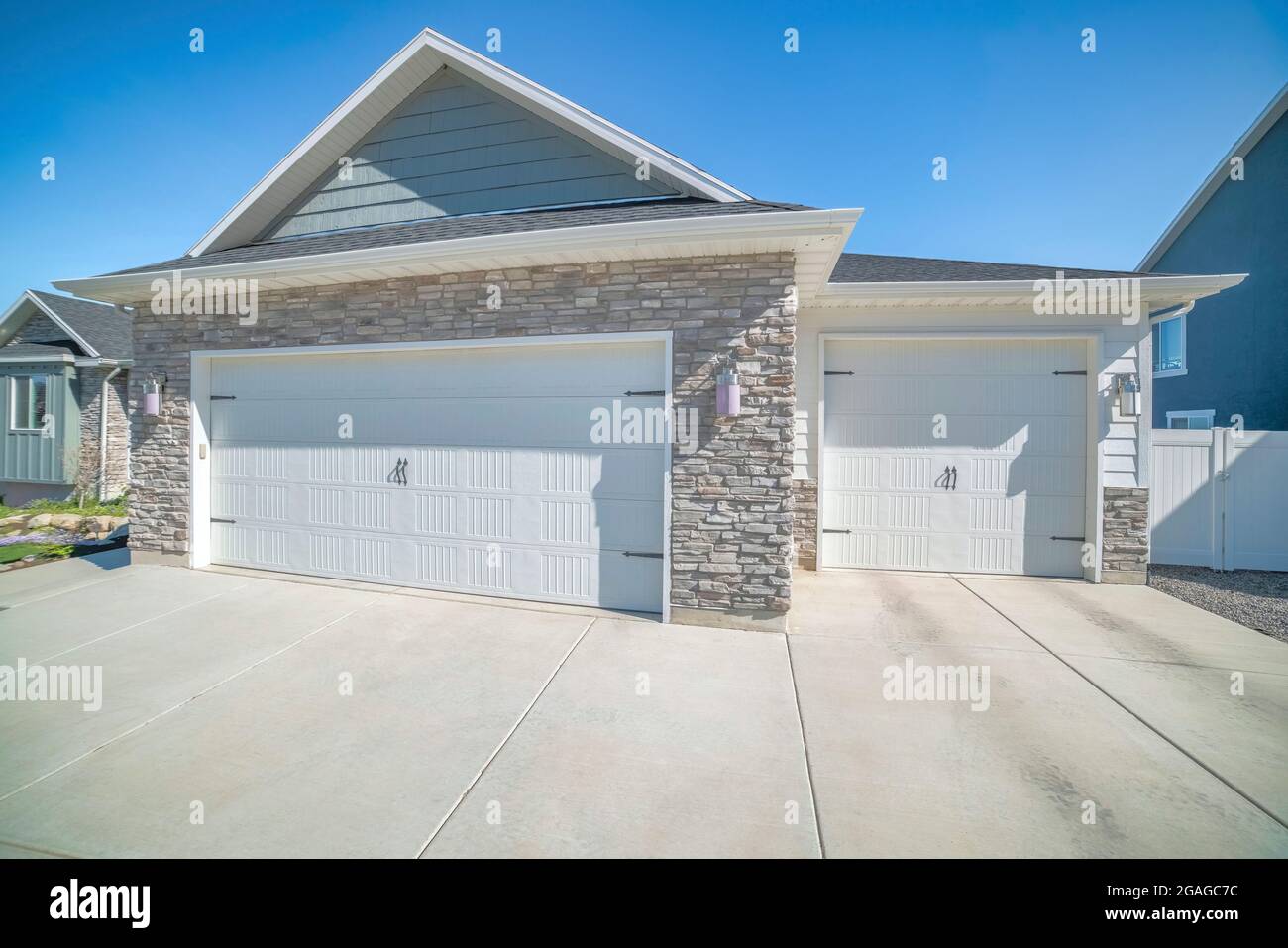 Threecar side hinged garage doors with stone veneer wall siding Stock
