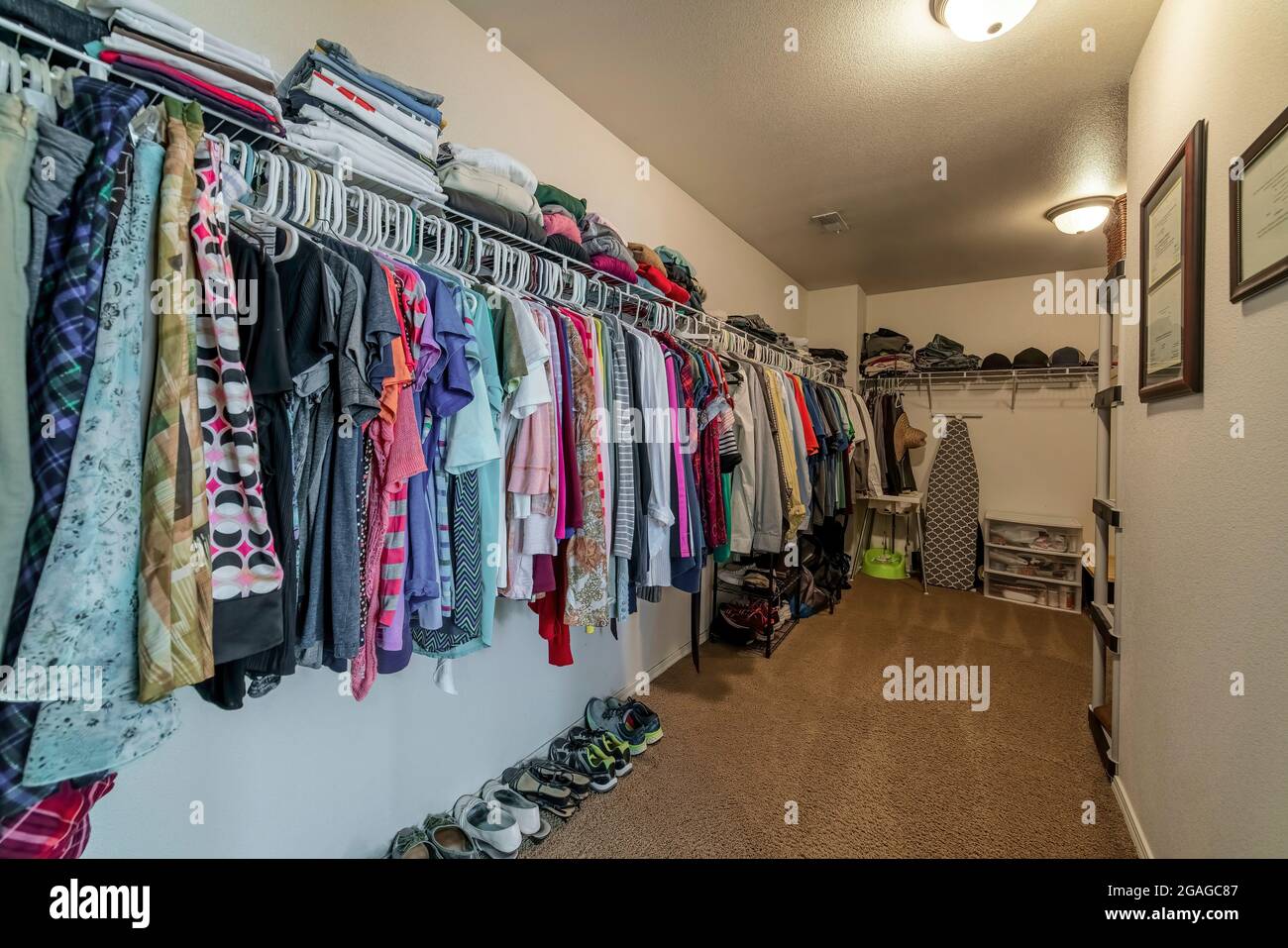 Walk in closet with organized hanging and stacked clothes and shoes Stock Photo