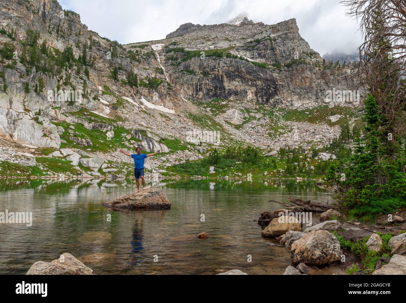 A hiker ventures out to a rock by the shore of Amphitheater Lake in Grand Teton National Park Wyoming USA Stock Photo Alamy