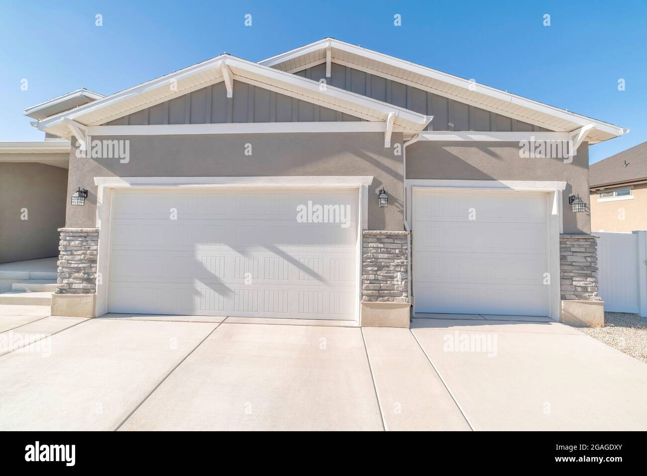Exterior of an attached threecar garage with white doors Stock Photo