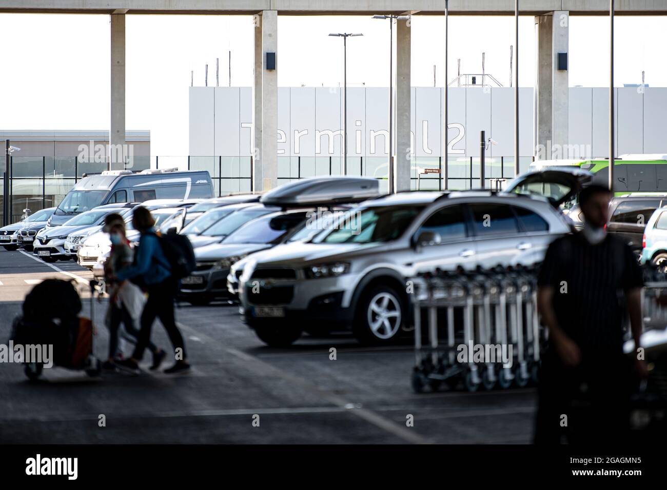 30 July 2021, Berlin, Schönefeld: Several cars are parked in front of the main hall of Berlin Brandenburg Airport (BER). Photo: Fabian Sommer/dpa Stock Photo