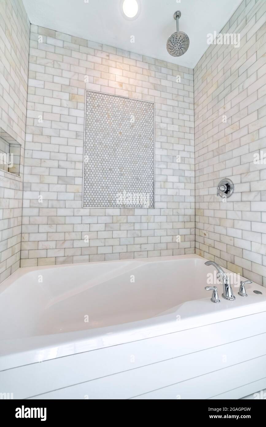 Alcove bathtub with marble subway tile surround and shower head Stock