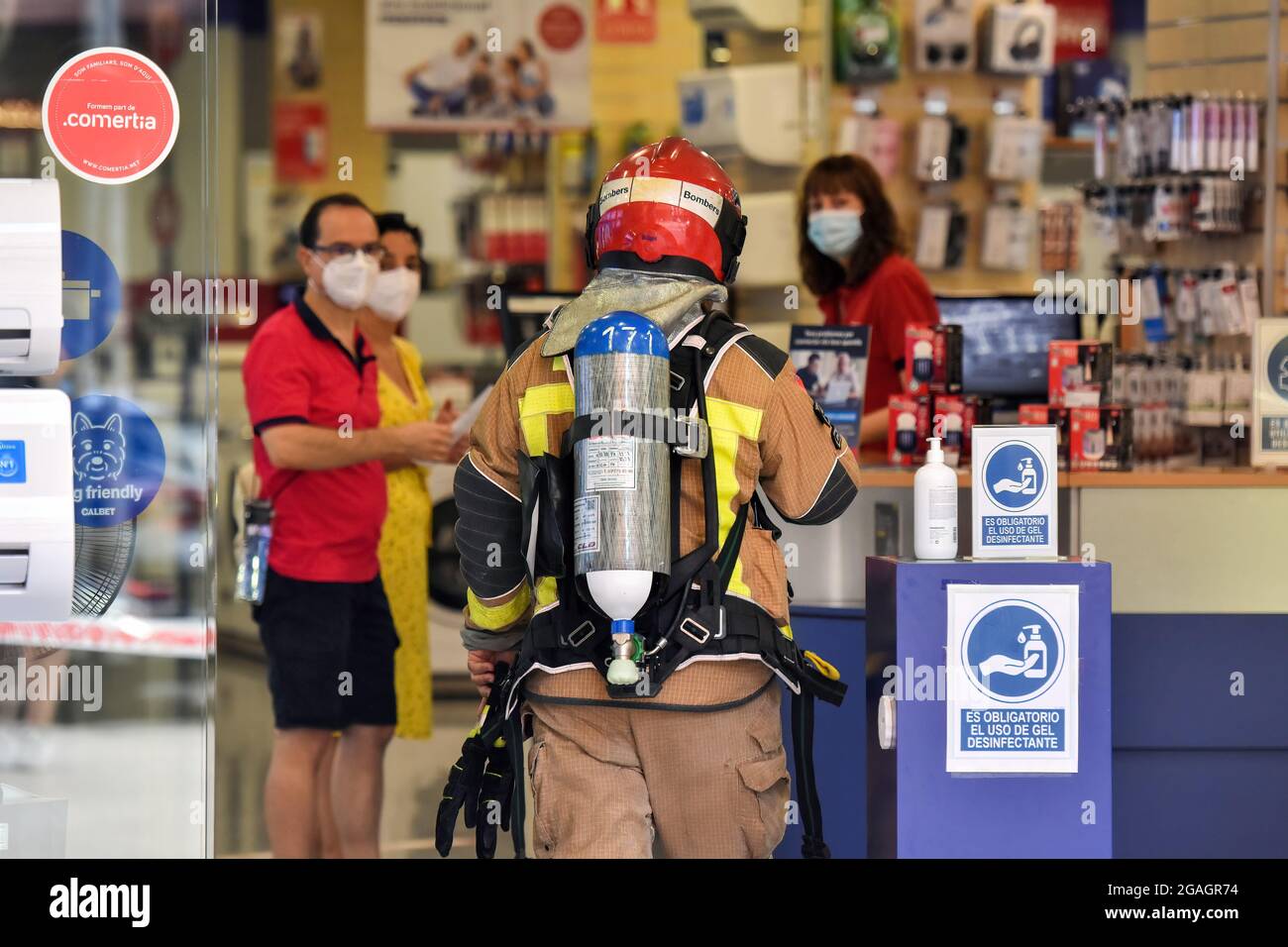 A Catalonia Firefighter talks with the workers of an electrical appliance store about a possible gas leak in Vendrell. A strong smell of gas alerted the residents of San Jordi Street, Vendrell where three teams of Catalonia Firefighters and several Local Police patrols attended closing access to the affected area. Firefighters with the help of technicians of the gas company began the gas measurements since the smell was coming from the underground sewer network and the presence of vapors or levels of propane, butane or natural gas was ruled out, hence a gas leak was ruled out and the possibili Stock Photo