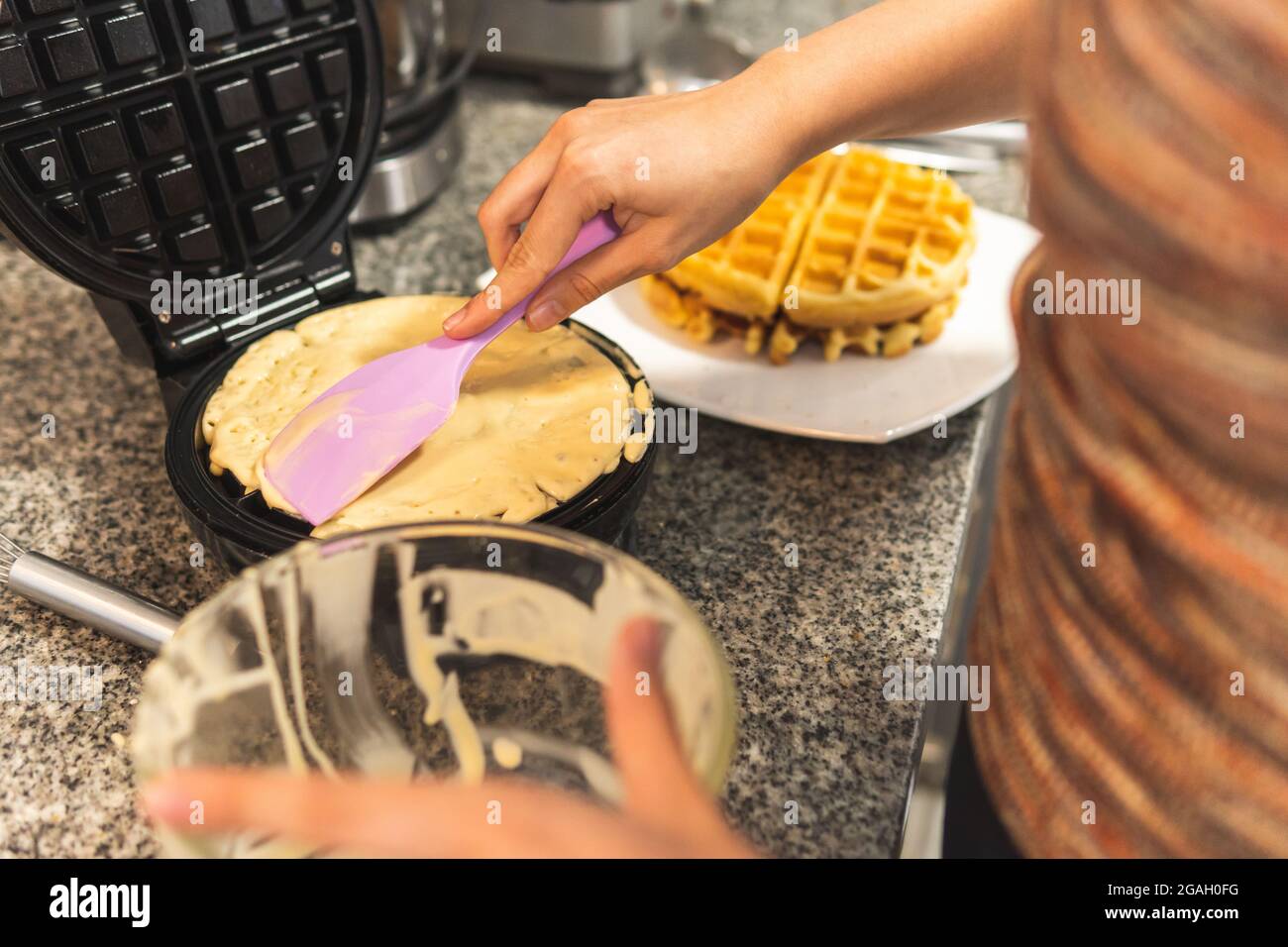 close-up of a woman's hands placing dough in a waffle iron Stock Photo