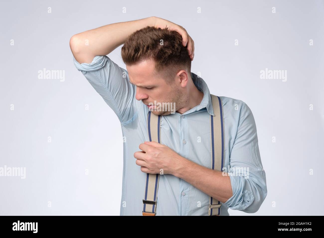 Young caucasian man looking on a sweat stain at a loss. Stock Photo