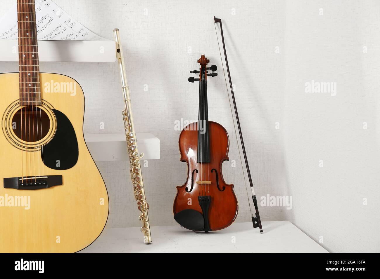 Musical instruments on decorated shelves against white wall background