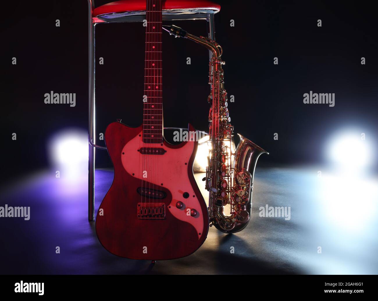 Beautiful golden saxophone and guitar near bar stool on a scene Stock