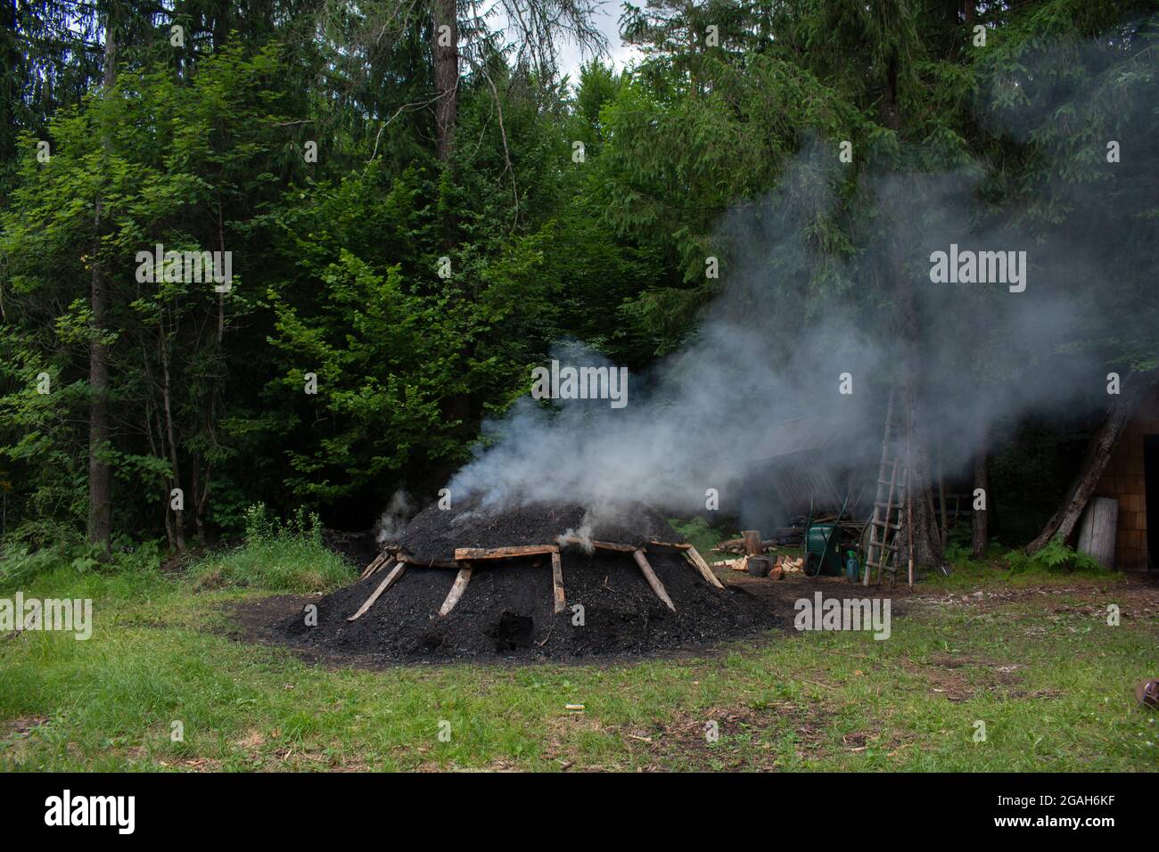 Traditional Charcoal making in Gozd Martuljek. Slovenia. Smoking mound of wood. Stock Photo