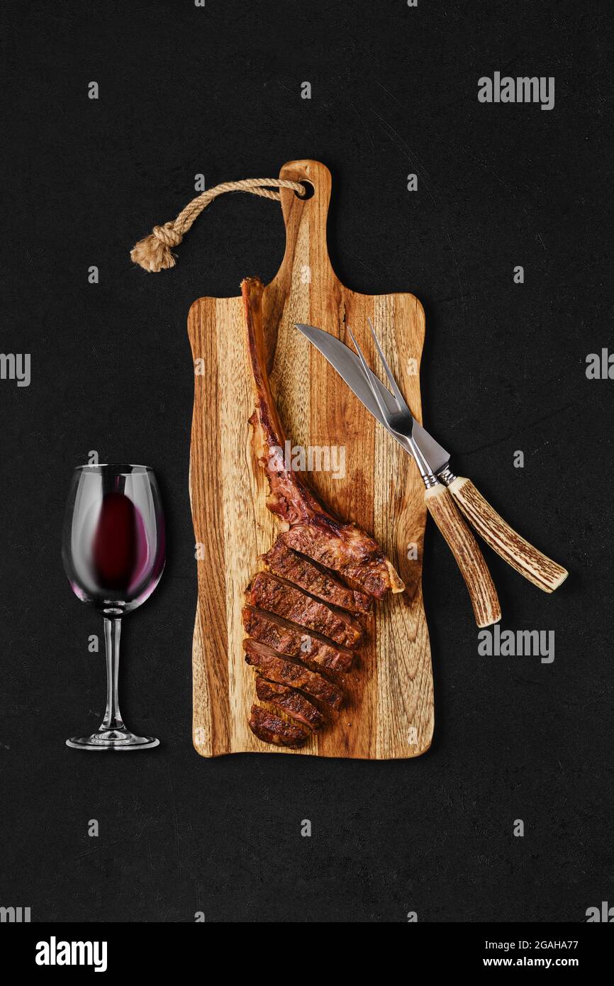Tomahawk steak cut on slices on wooden board Stock Photo