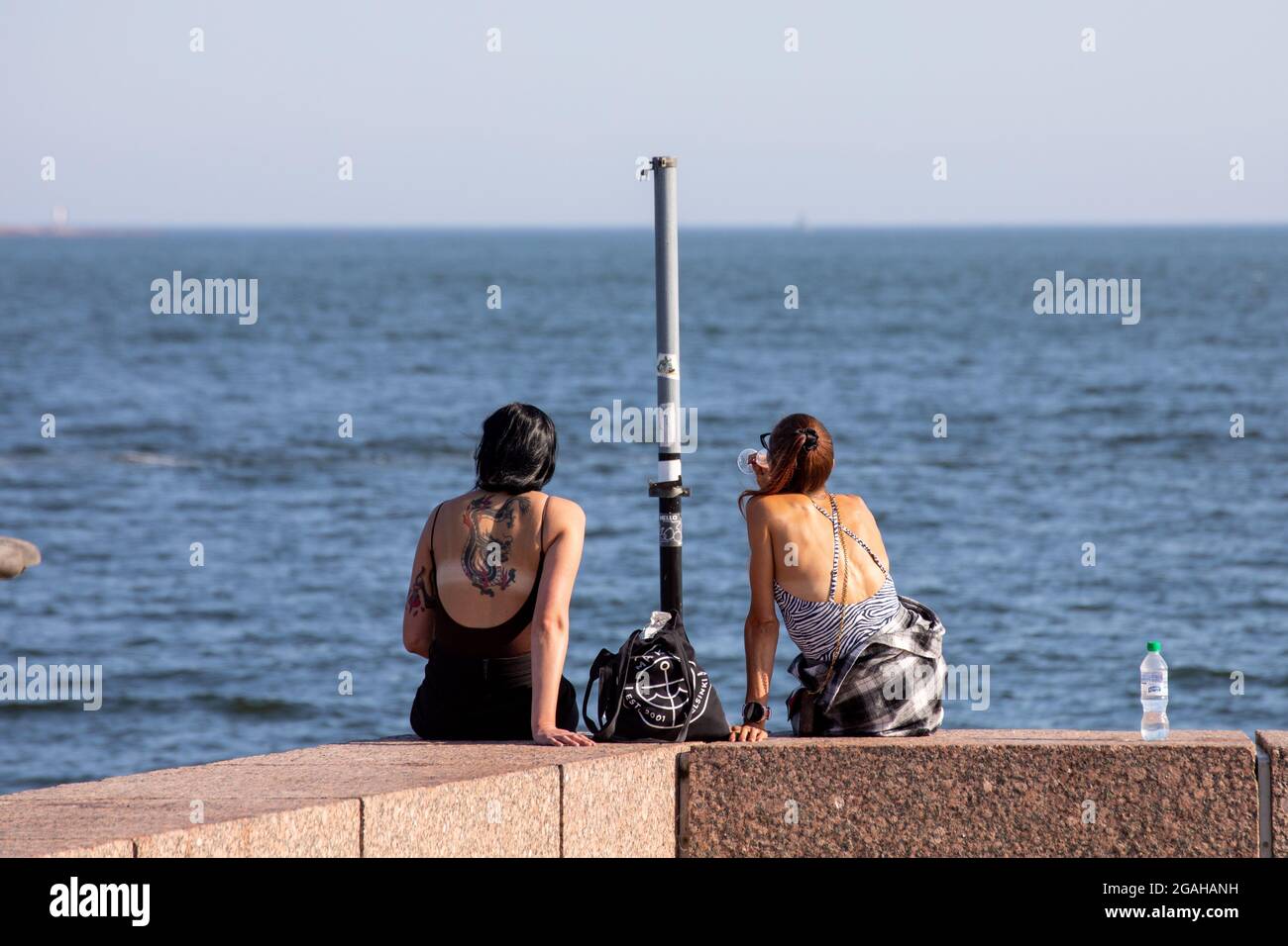 Two women sitting on the dock on a warm summer evening in Eira district of Helsinki, Finland Stock Photo