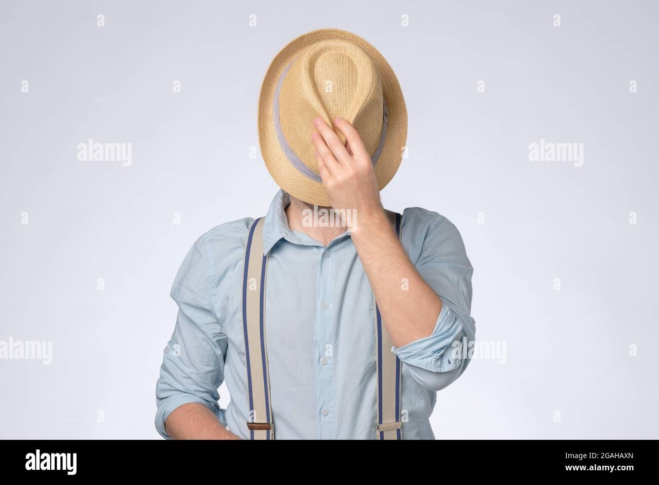 Young man in blue shirt covered his eyes by summer hat Stock Photo