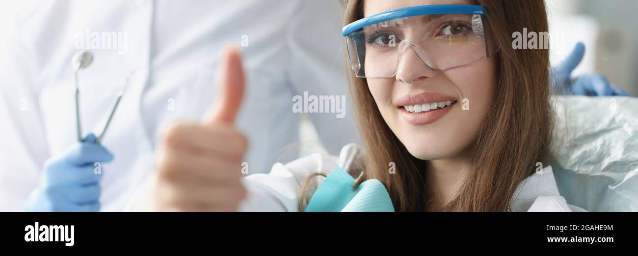 Portrait of smiling woman holding her thumbs up at dentist appointment Stock Photo