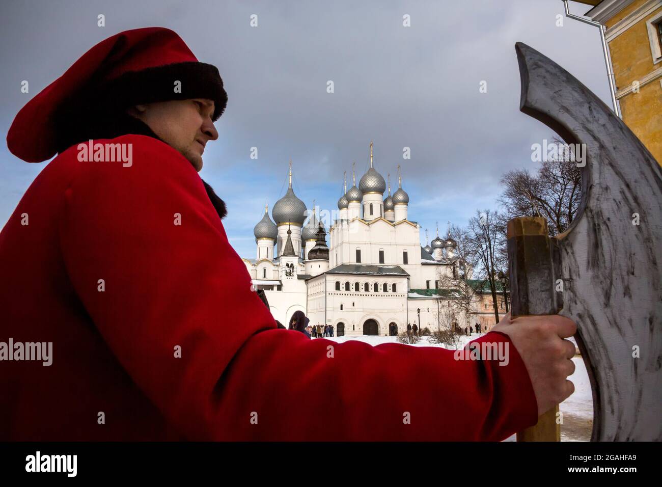 Rostov, Russia. 24th of February, 2017 A man in the clothes of an Old Russian Sagittarius (Streltsy) stands with an axe against the background of the Assumption Cathedral and the Gate Church of the Resurrection on the territory of the Kremlin in Rostov the Great town, Yaroslavl region, Russia Stock Photo