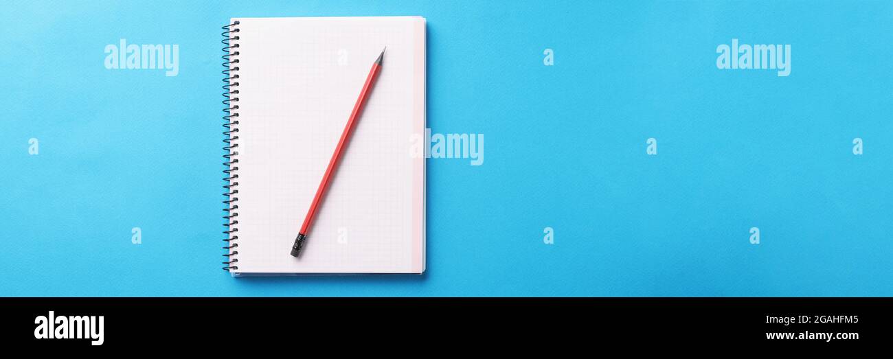 White notebook with wooden pencil lies on blue background Stock Photo