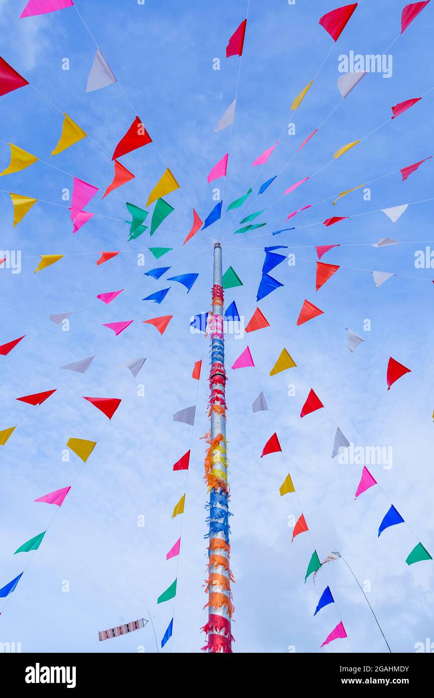vivid color of Thai's style fancy party flag strips decoration on a fancy still pole with blue sky and white cloud in background Stock Photo