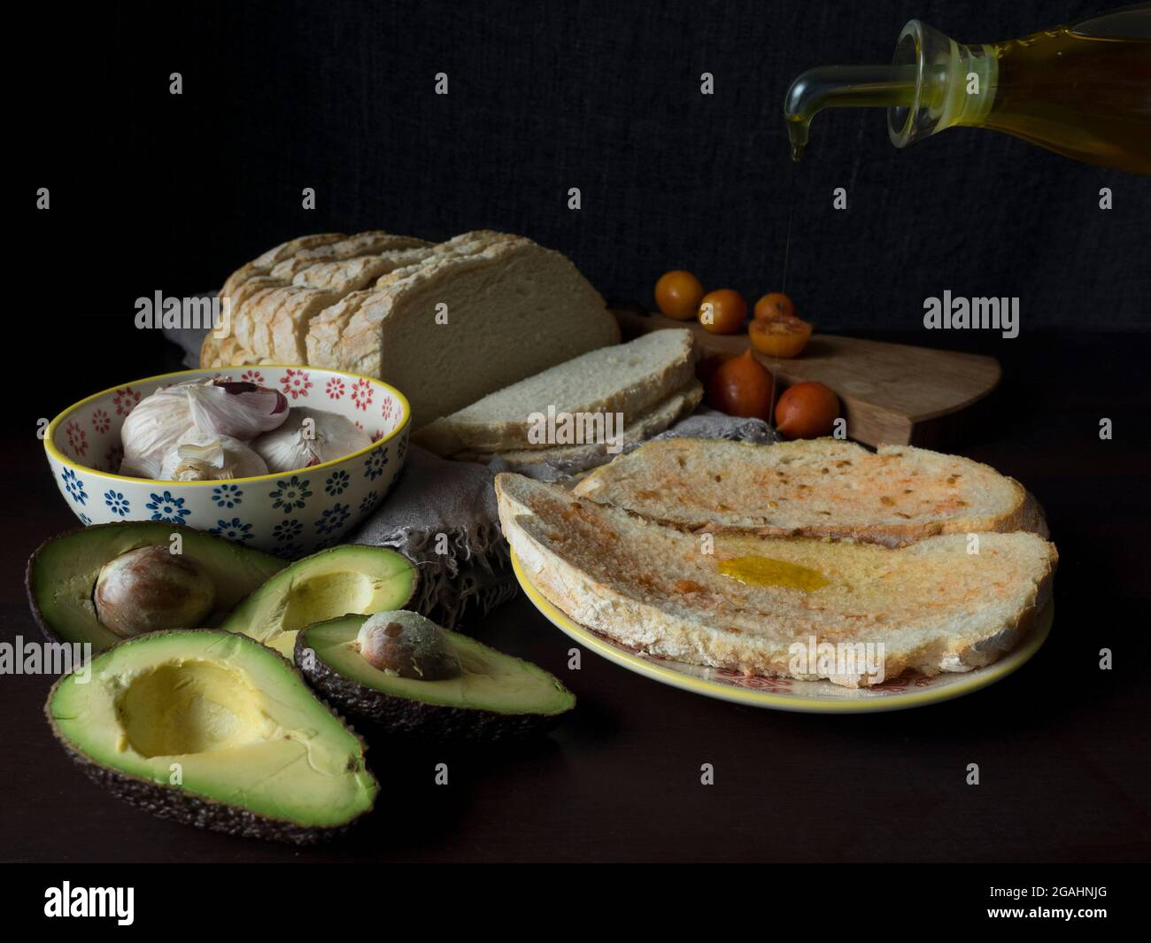 Oil machine pouring oil on bread with tomato, garlic and avocado Stock