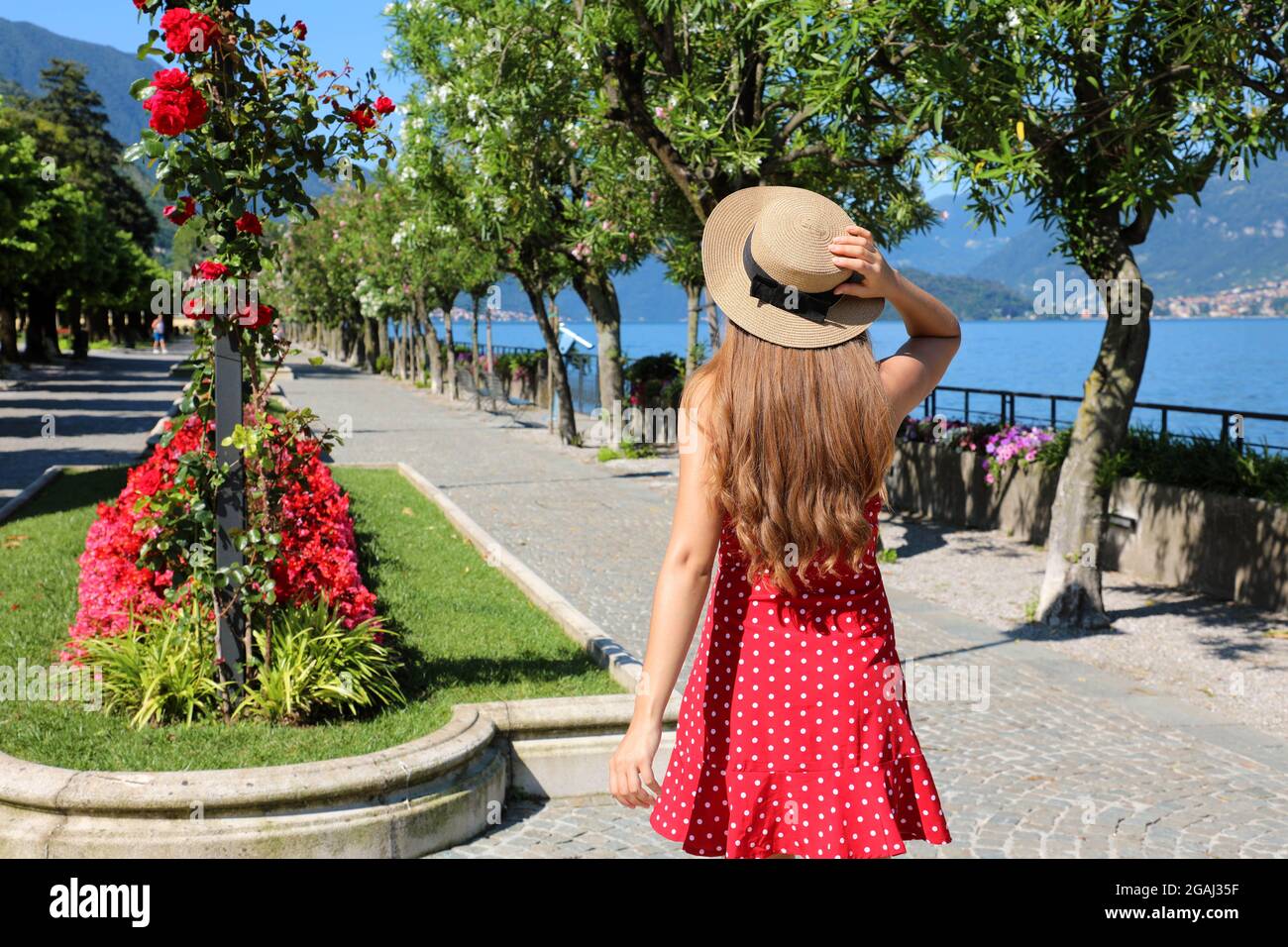 Charming young woman walking along Bellagio flowered promenade on Lake Como, Italy Stock Photo