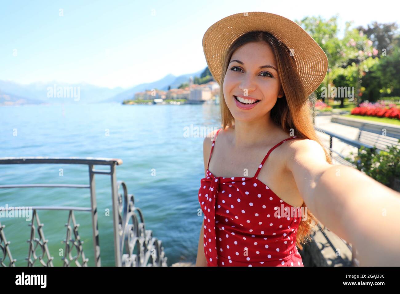 Adorable young woman with hat making selfie photo on Lake Como. Self portrait girl posing in Bellagio, Italy. Stock Photo