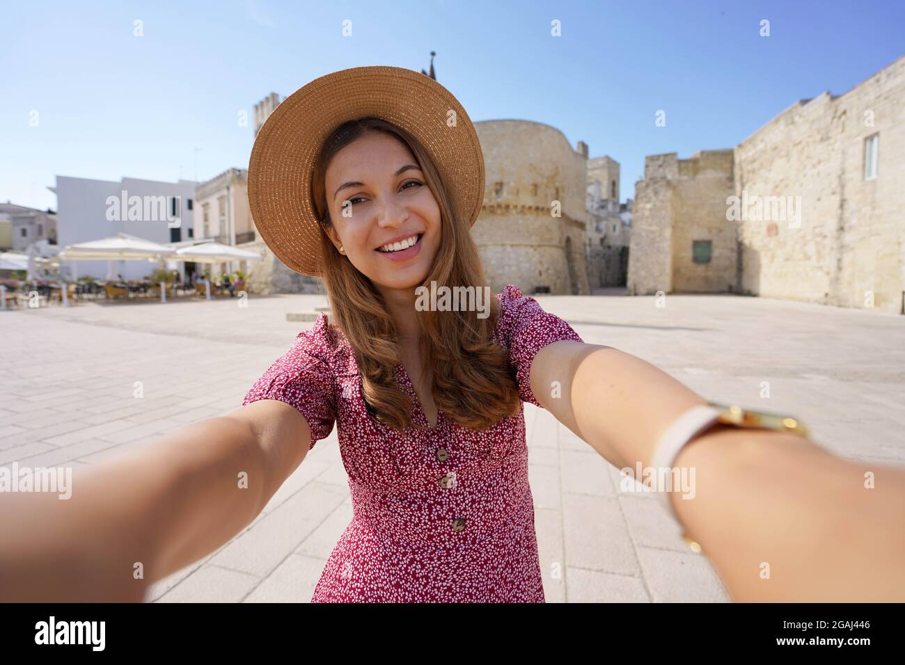 Proximity tourism concept. Smiling woman taking self portrait in Apulia with the old town of Otranto on the backgorund, Italy Stock Photo