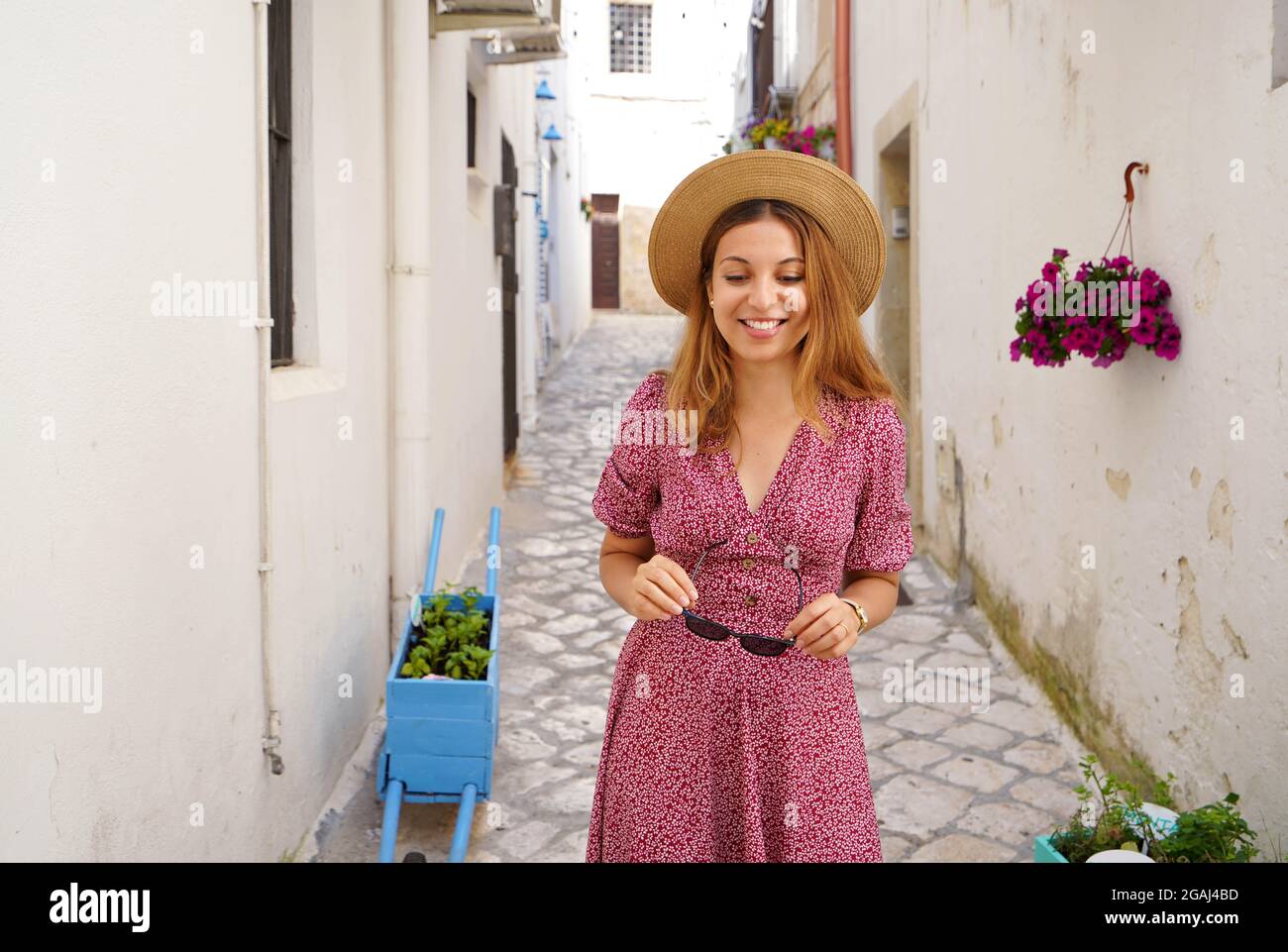Attractive fashion woman walking looking down in narrow alley of typical old town of Italy Stock Photo