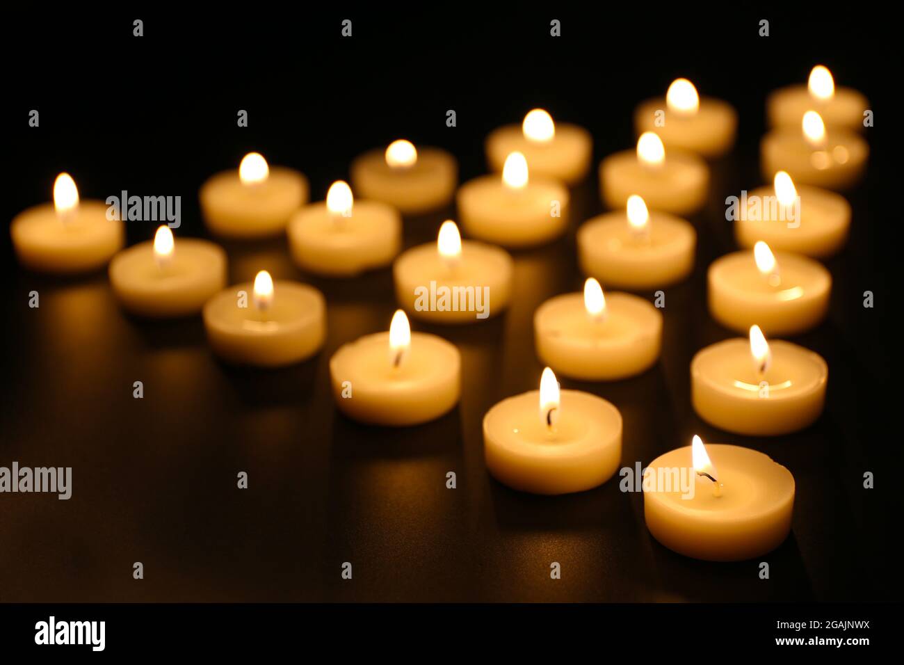Alight candles in a row on black background Stock Photo - Alamy
