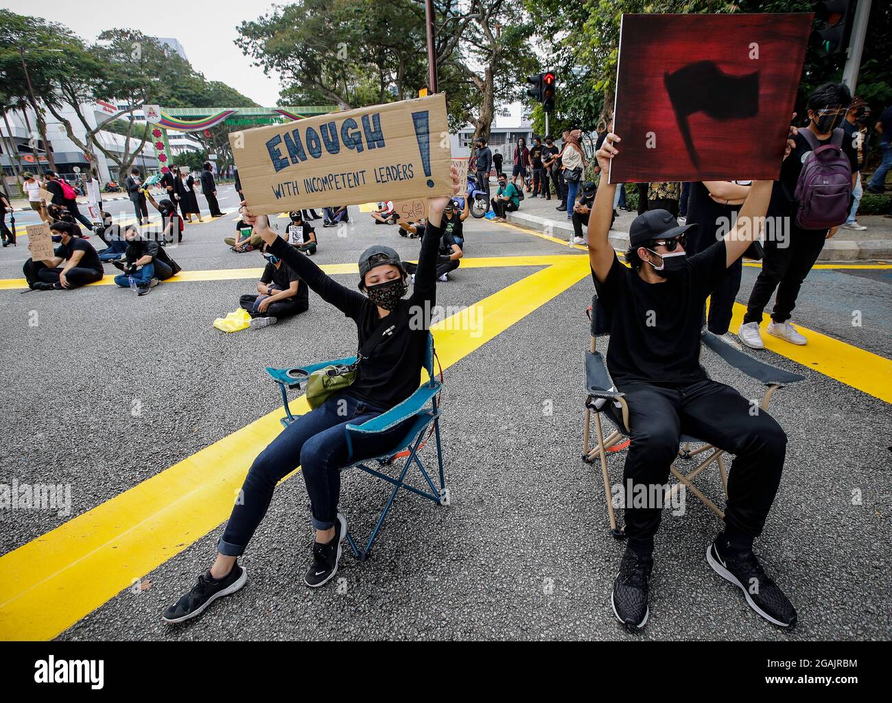 Kuala Lumpur, Malaysia. 31st July, 2021. Protesters hold placards while  sitting on chairs on the middle of the road during the  demonstration.Hundreds of black-clad Malaysians staged an anti-government  protest near the Independence