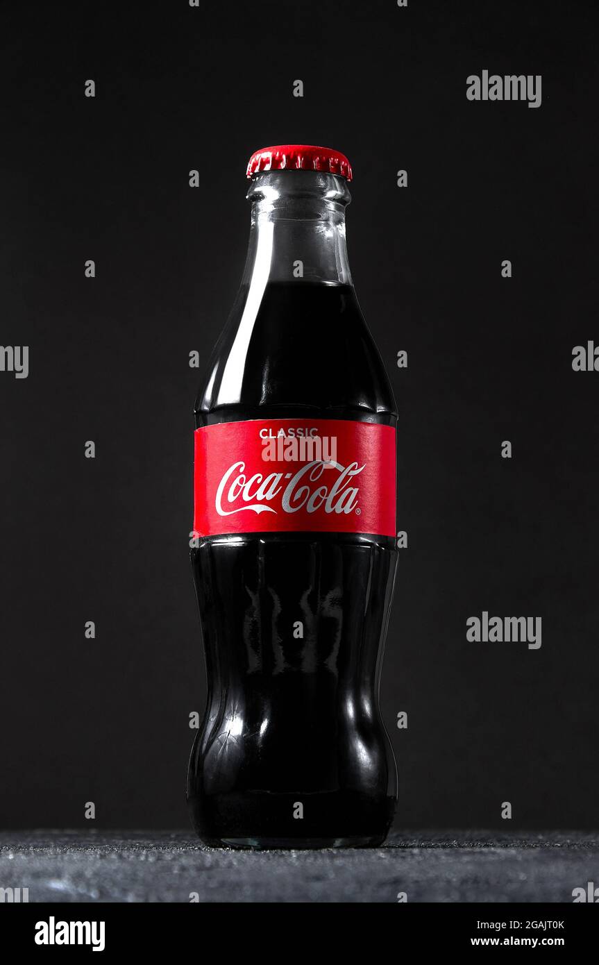 Lugansk, Ukraine - July 25, 2021: Coca Cola in glass bottle on dark background. Creative minimal concept. Stock Photo