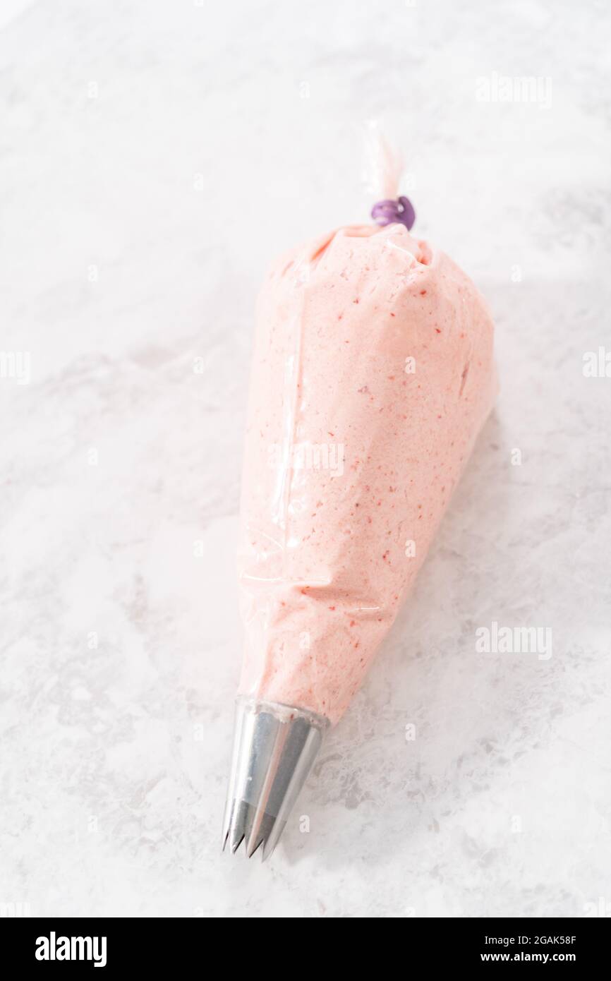 Strawberry buttercream frosting in a piping bag with a large metal piping tip Stock Photo Alamy