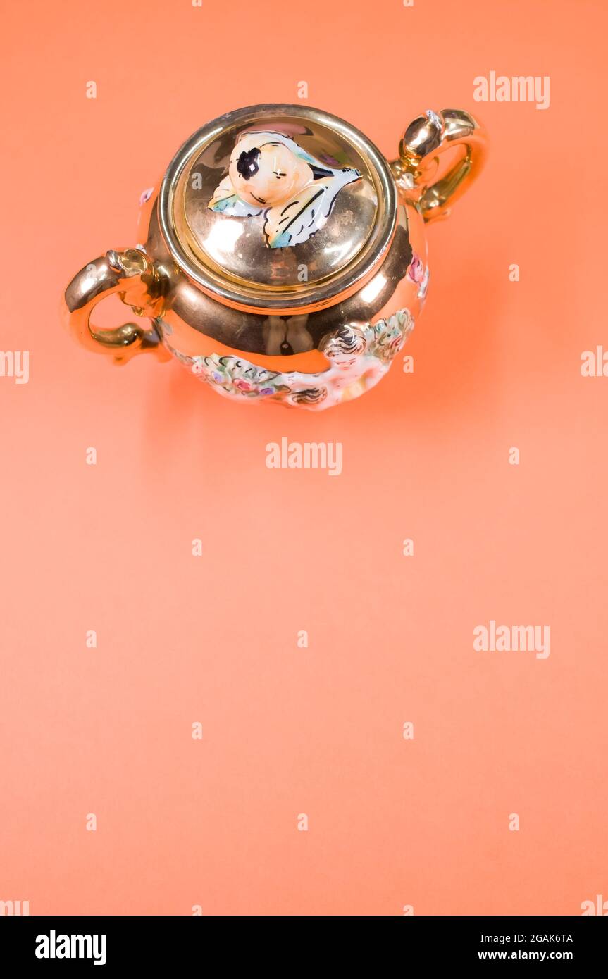 Vertical sh of a vintage sugar pot with a lid, placed on an orange