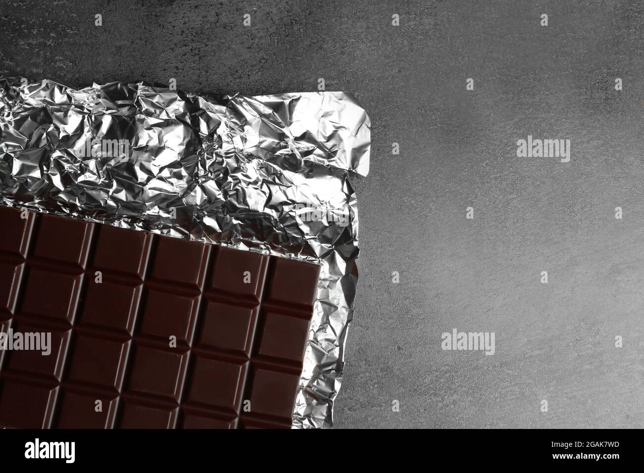 Chocolate bar in foil on gray background Stock Photo - Alamy