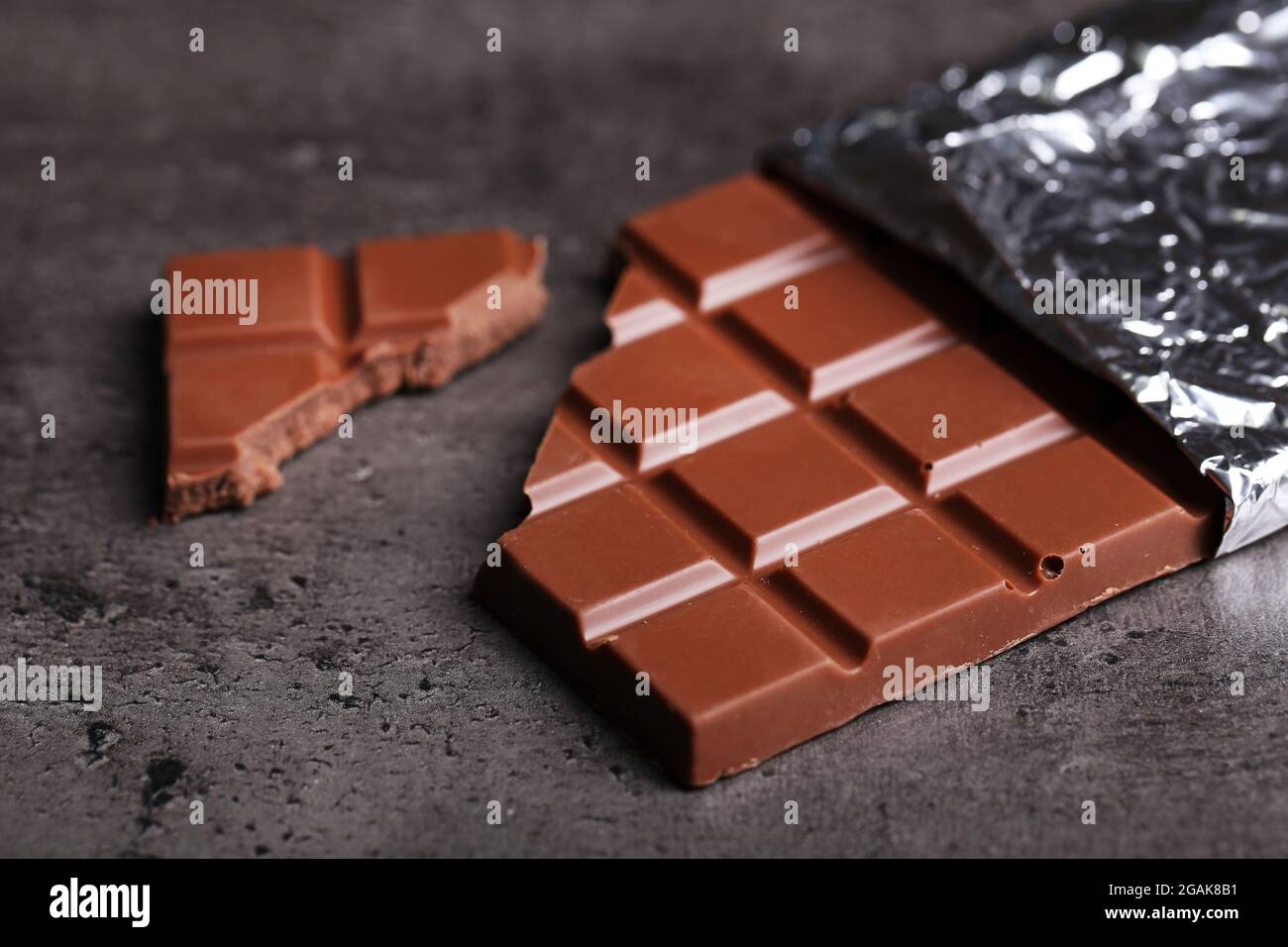 Chocolate bar in foil on gray background Stock Photo - Alamy